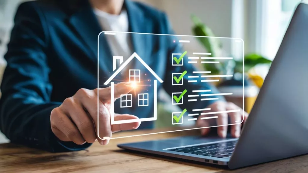 Person interacting with a digital interface displaying a house icon and a checklist with green checkmarks next to tasks on a laptop